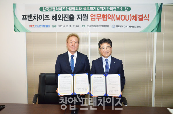 정현식 한국프랜차이즈산업협회장(오른쪽)과 이문국 글로벌기업위기관리연구소 대표(왼쪽)가 협약서를 들고 기념 촬영을 하고 있다.